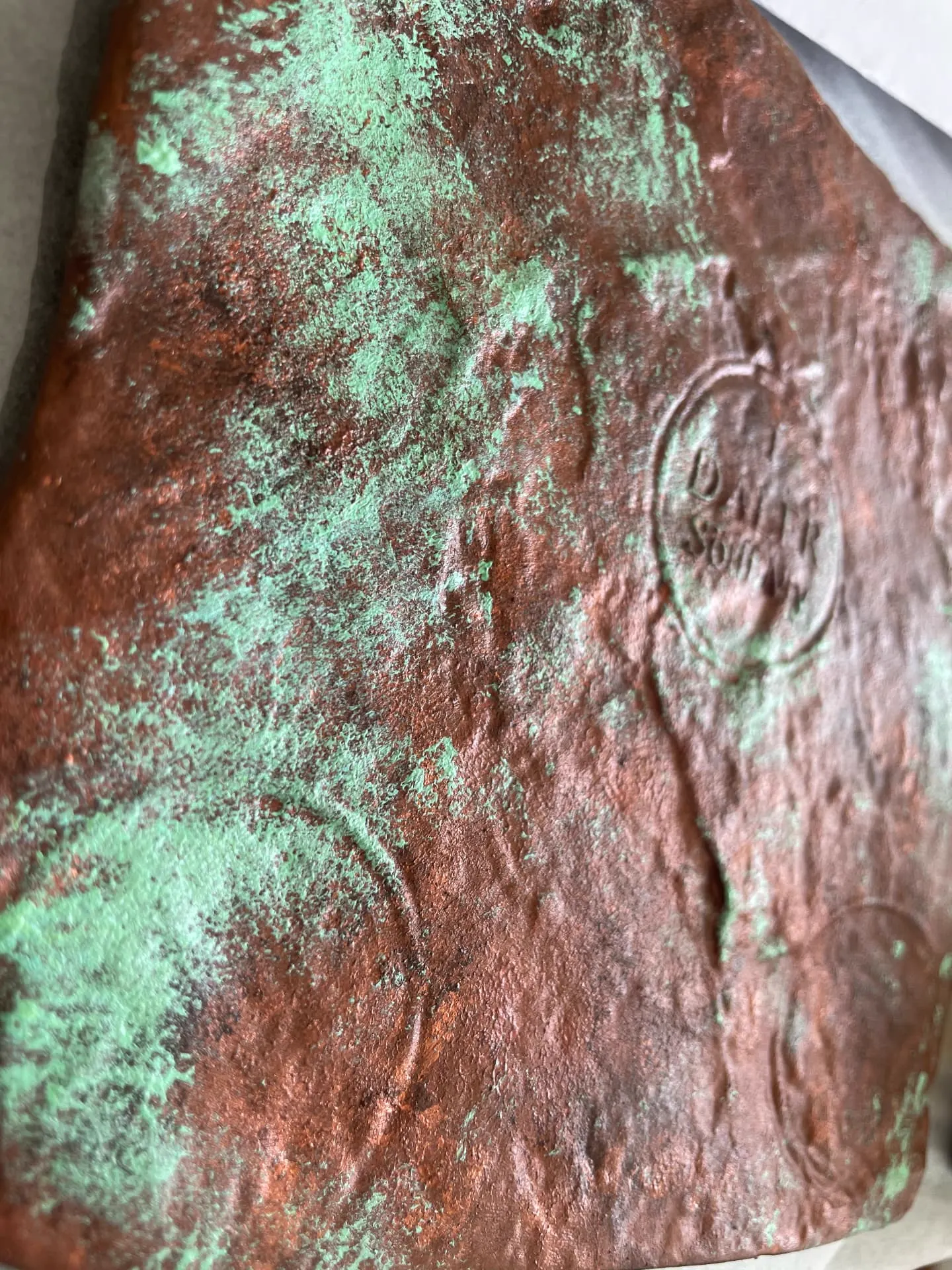 Närbild på myntplåt med kopparton och grön patina
